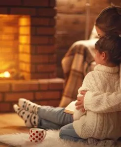 Mother with a young child in front of a fireplace.