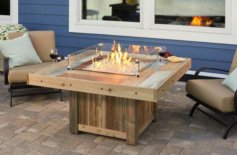 Wooden square outdoor fireplace with glass sides around central fire.