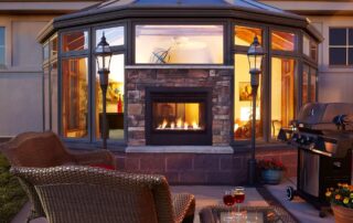 Twilight II Modern Indoor/Outdoor See-Through Fireplace between a sun porch and patio.