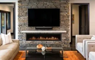 Contemporary living room featuring a linear gas fireplace built into a stacked stone wall with a mounted TV and modern furniture.