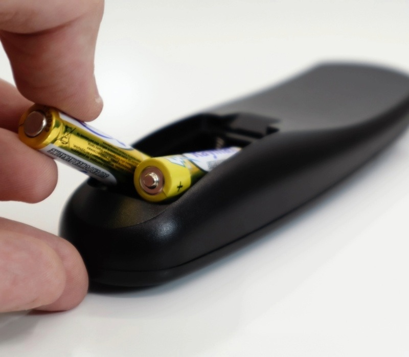 Upclose shot of a hand changing batteries in a remote.