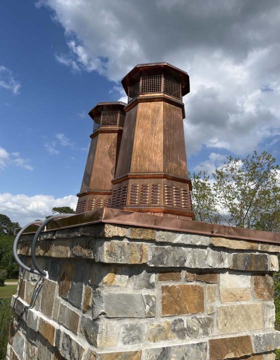 Two European Copper King style chimney caps Two European Copper King style chimney caps with octagonal tapered design and louvered vents installed on a natural fieldstone chimney with copper flashing.