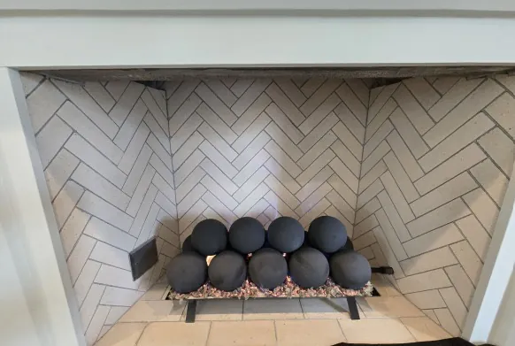 Rasmussen 6-inch black Fireball Set with 30-inch match-lit burner Rasmussen 6-inch black Fireball Set with 30-inch match-lit burner installed in a FireRock 48-inch California Conventional fireplace with herringbone tile surround.