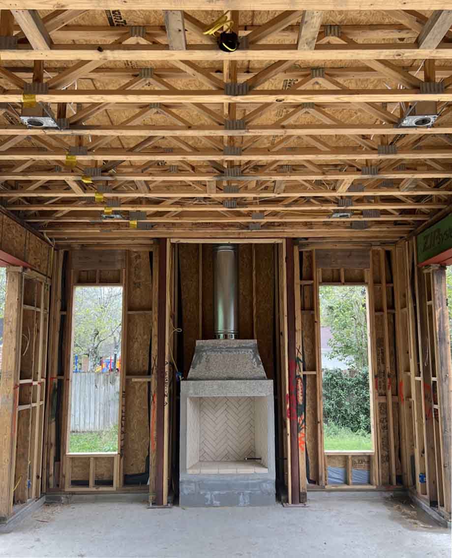 Isokern Magnum 42-inch pre-engineered masonry fireplace with herringbone firebrick and stainless steel flue pipe during framing of an outdoor living space, Perfection Supply, Houston, TX.
