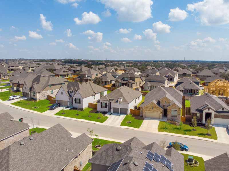 Aerial view of a Houston-area subdivision with homes and new construction framing, reflecting the range of building conditions performance-based energy plans account for.
