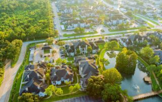 Aerial view of a Houston, TX residential neighborhood with tree-lined streets and a pond, illustrating homes covered by residential energy standards.