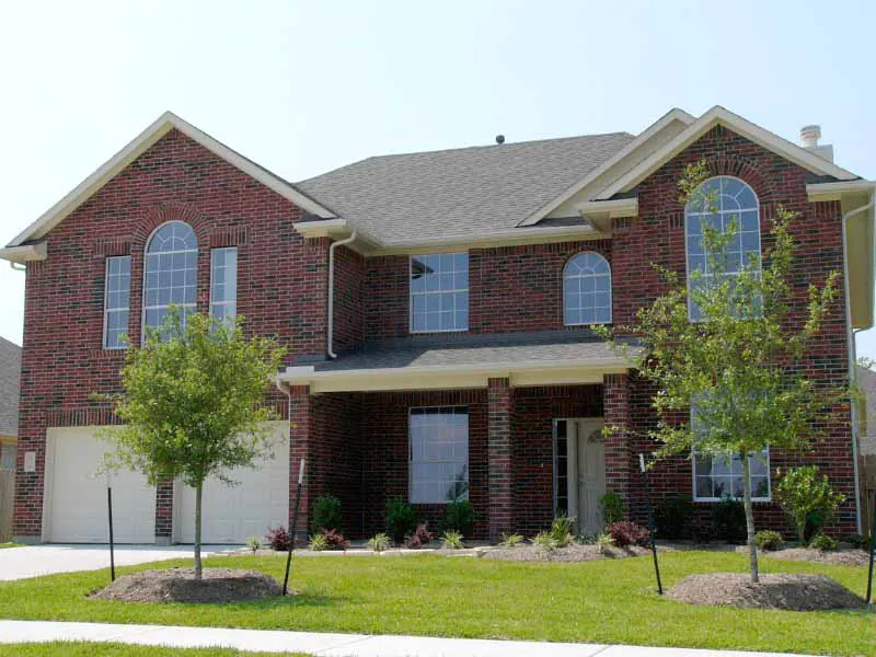 Two-story brick home exterior in the Houston, TX area, representing a house evaluated under prescriptive or performance energy code paths.