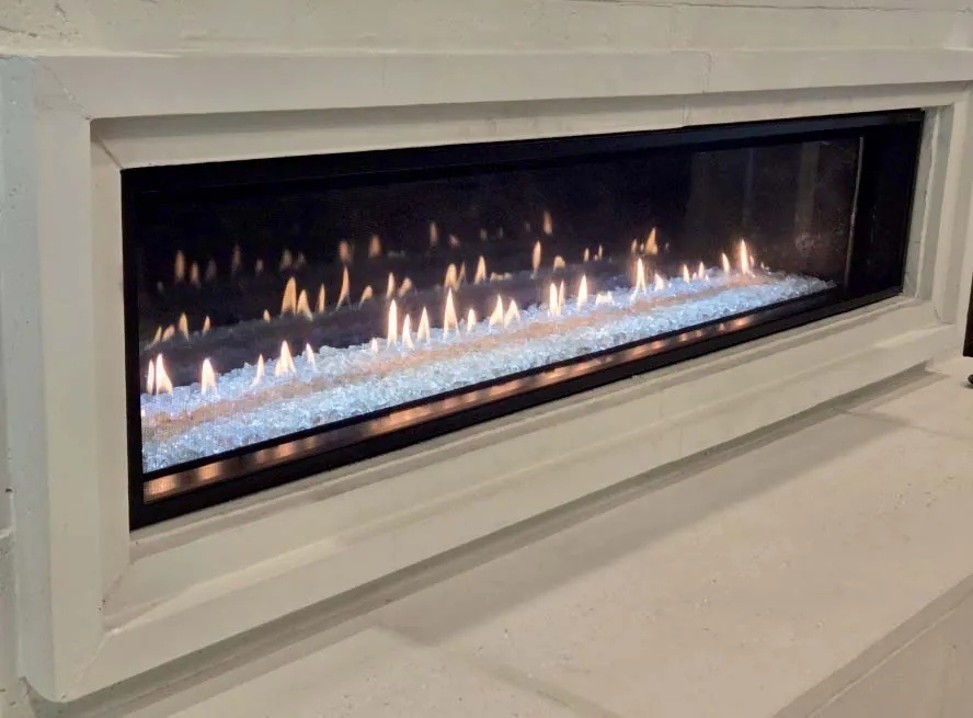 Close-up of a Heat & Glo Mezzo 72-inch linear gas fireplace burning over iced fog glass. Close-up of a Heat & Glo Mezzo 72-inch linear gas fireplace burning over iced fog glass.