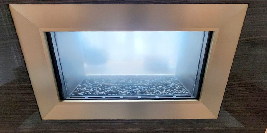 After: Clean glass and a strong, even flame after service. Stellar 4-foot see-through linear gas fireplace (model 4-ST-2-GL) after service by Perfection Supply in Houston, TX, burning with clear flames in a wood-veneer surround with a brass trim frame.